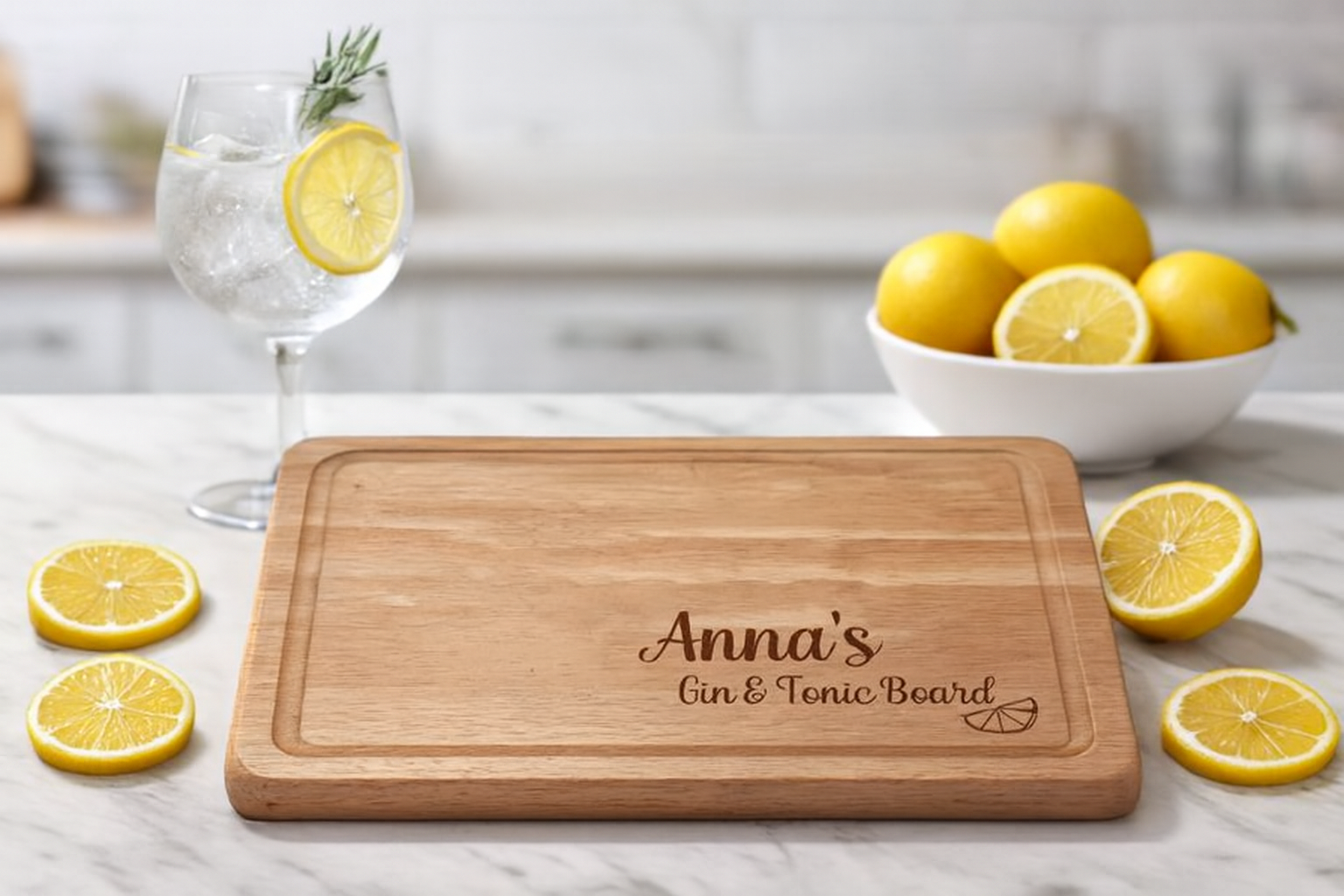 Wooden cutting board with 'Anna's Gin & Tonic Board' engraving on a kitchen counter with lemons and a glass of water.