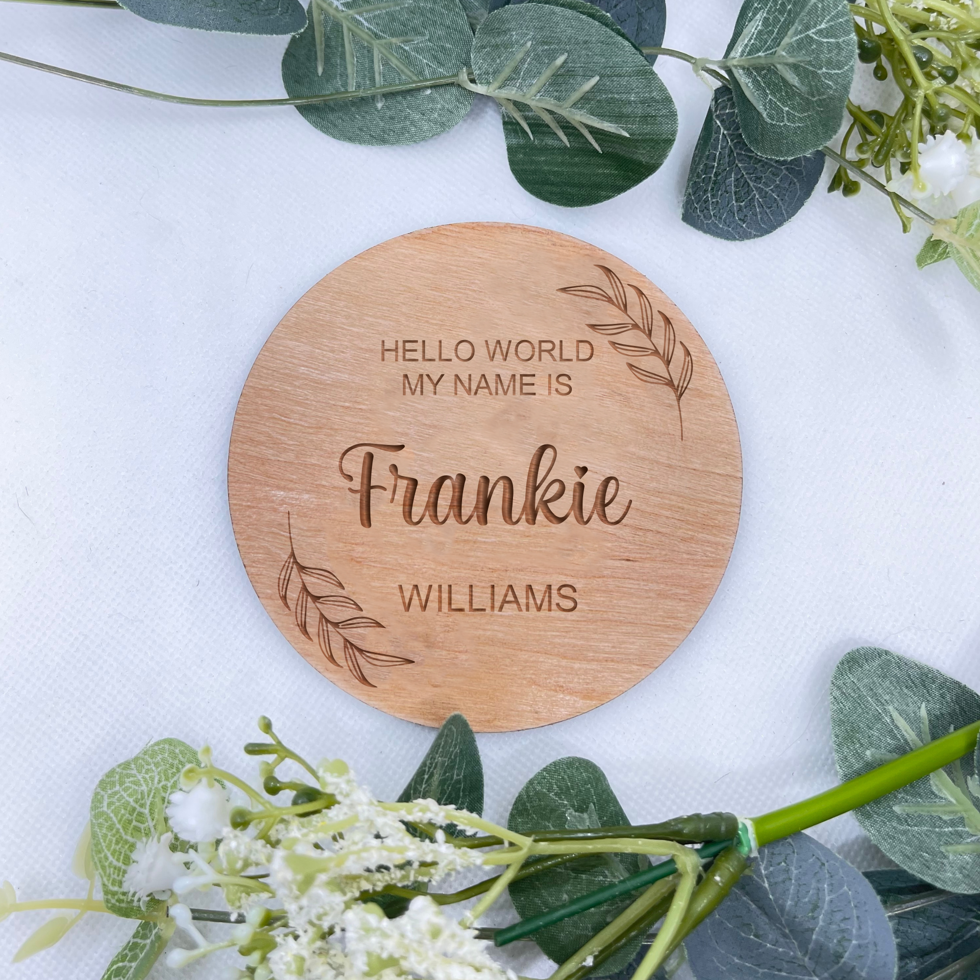 Wooden botanical pregnancy reveal sign with leaf engraving for newborn photography.