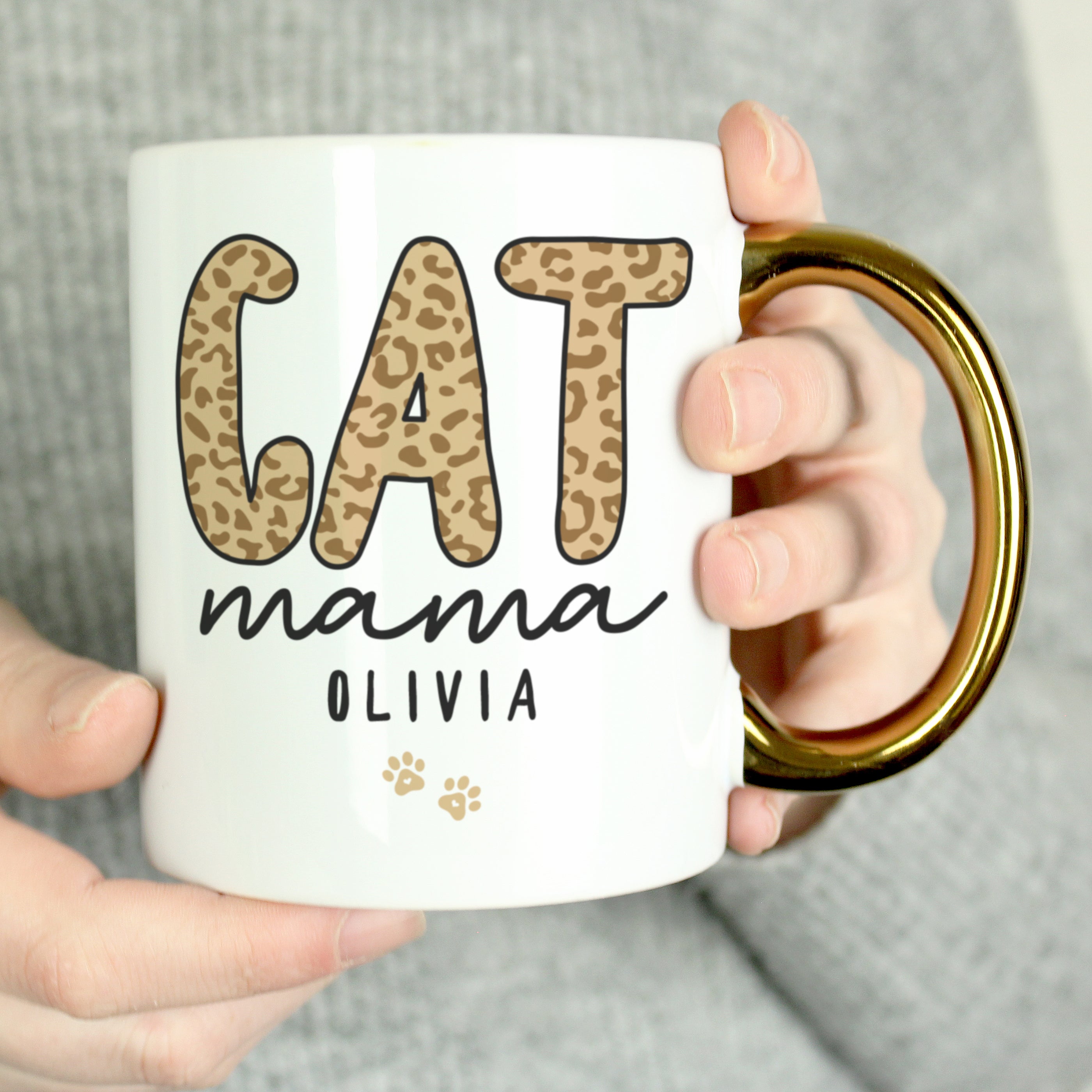 Person holding a white mug with 'CAT mama OLIVIA' text and leopard print design.
