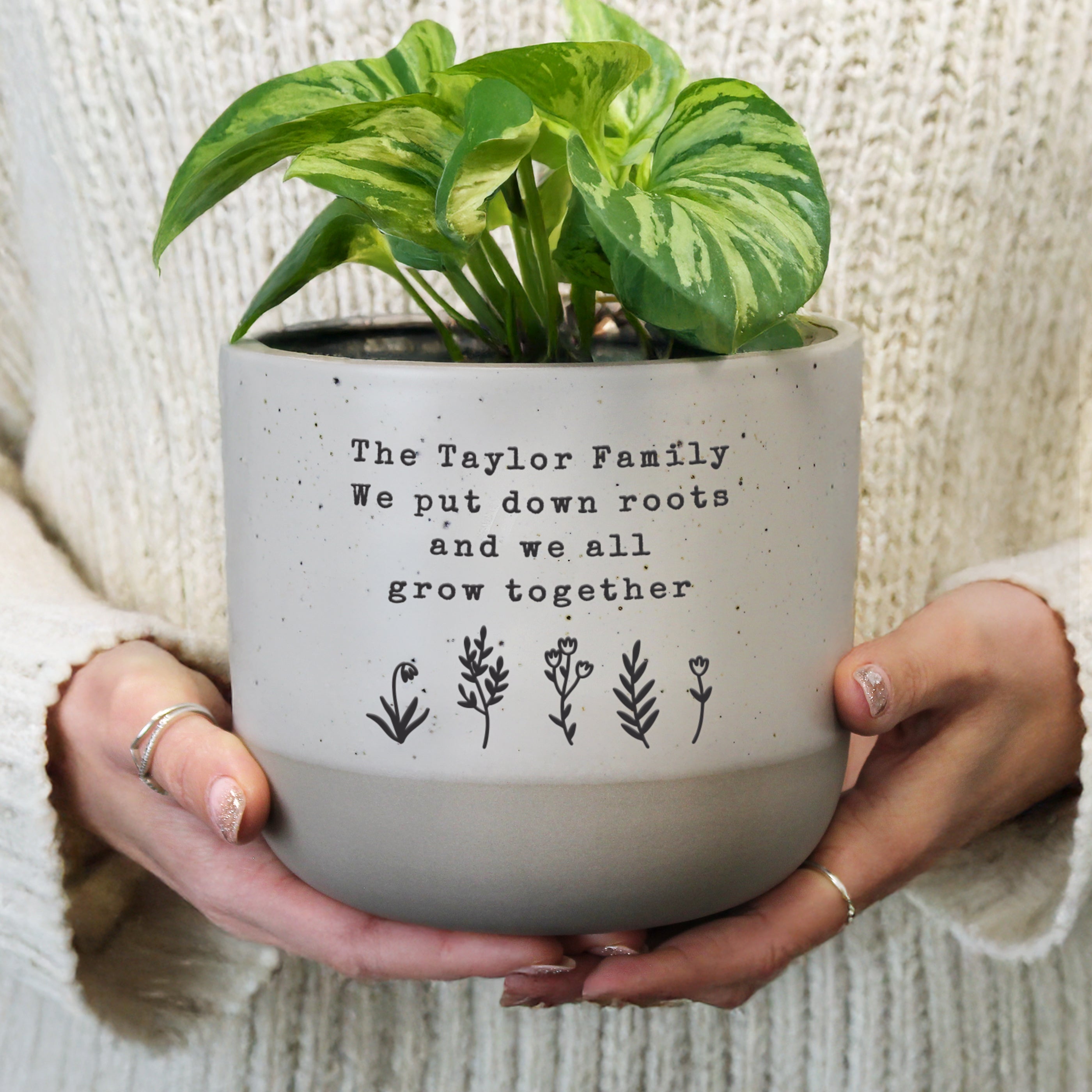 Person holding a potted plant with personalised text on a neutral background