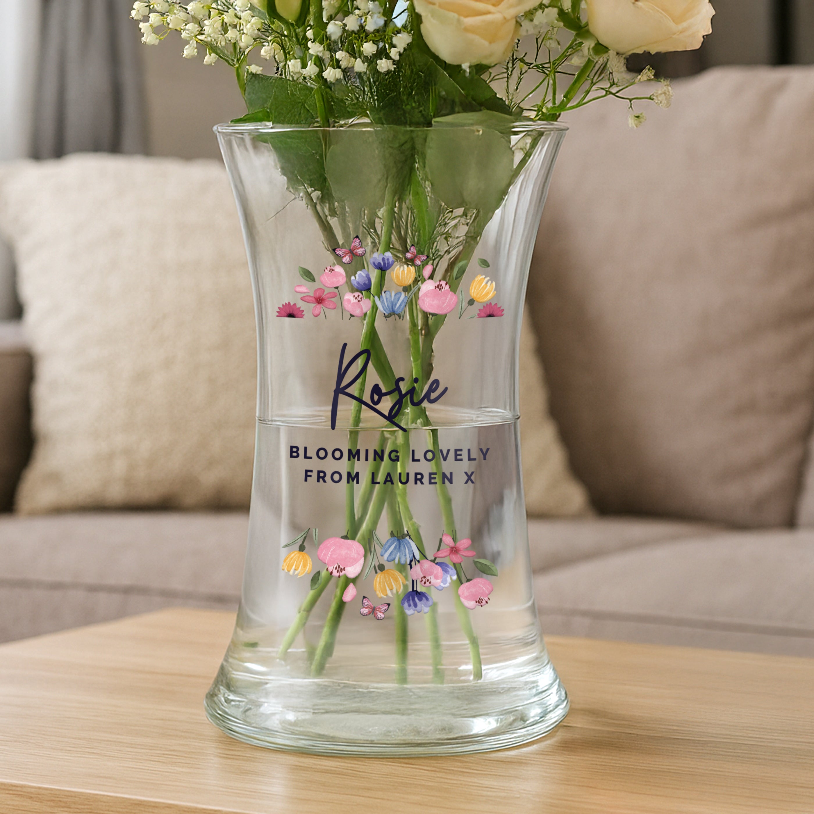 Clear vase with flowers and personalized text on a wooden table