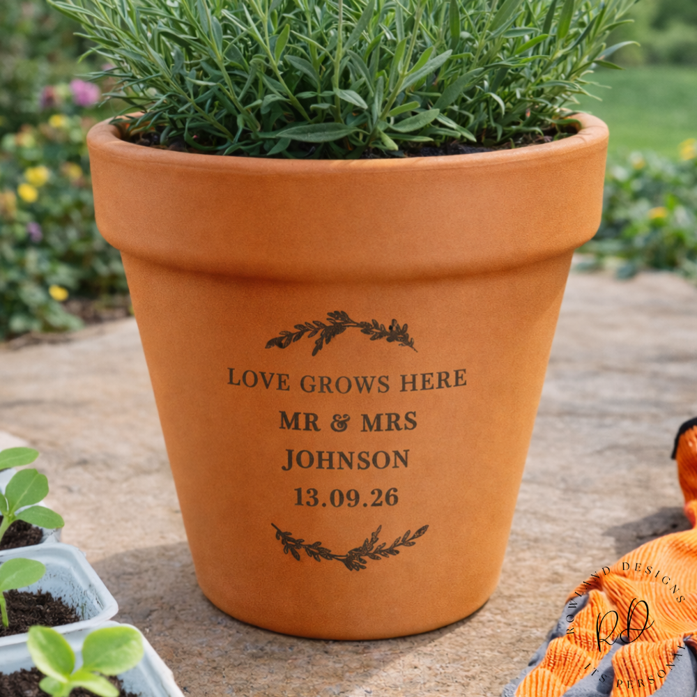Terracotta pot with engraved text on a gardening background, surrounded by plants.