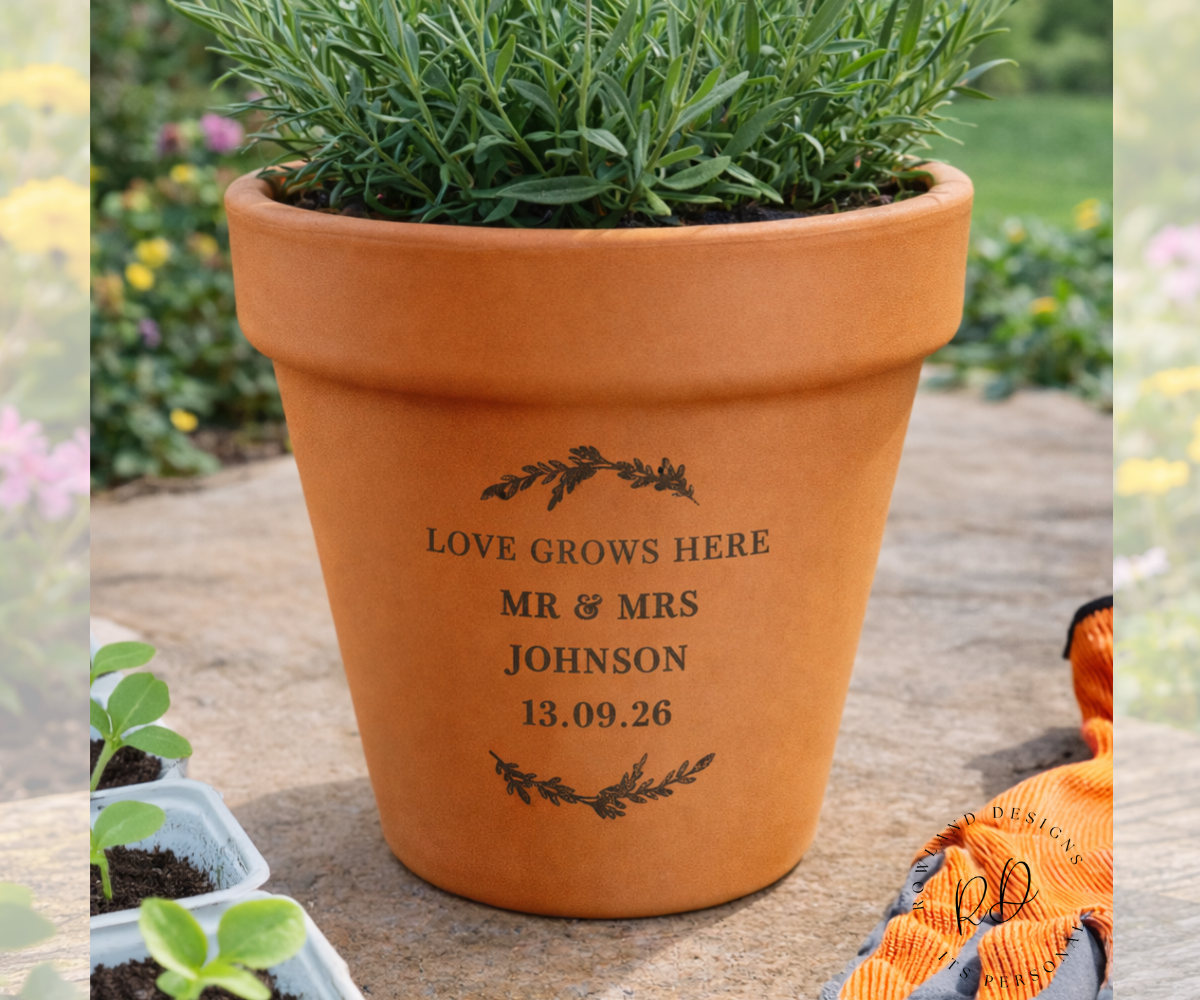 Terracotta pot with engraved text on a gardening background, surrounded by plants.