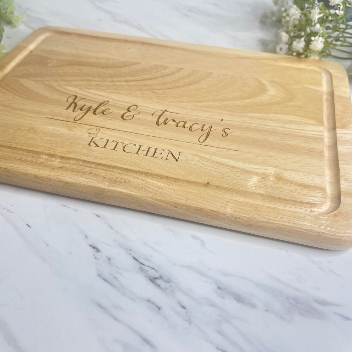 Close-up of the engraved name and chef hat on a personalised wooden chopping board.