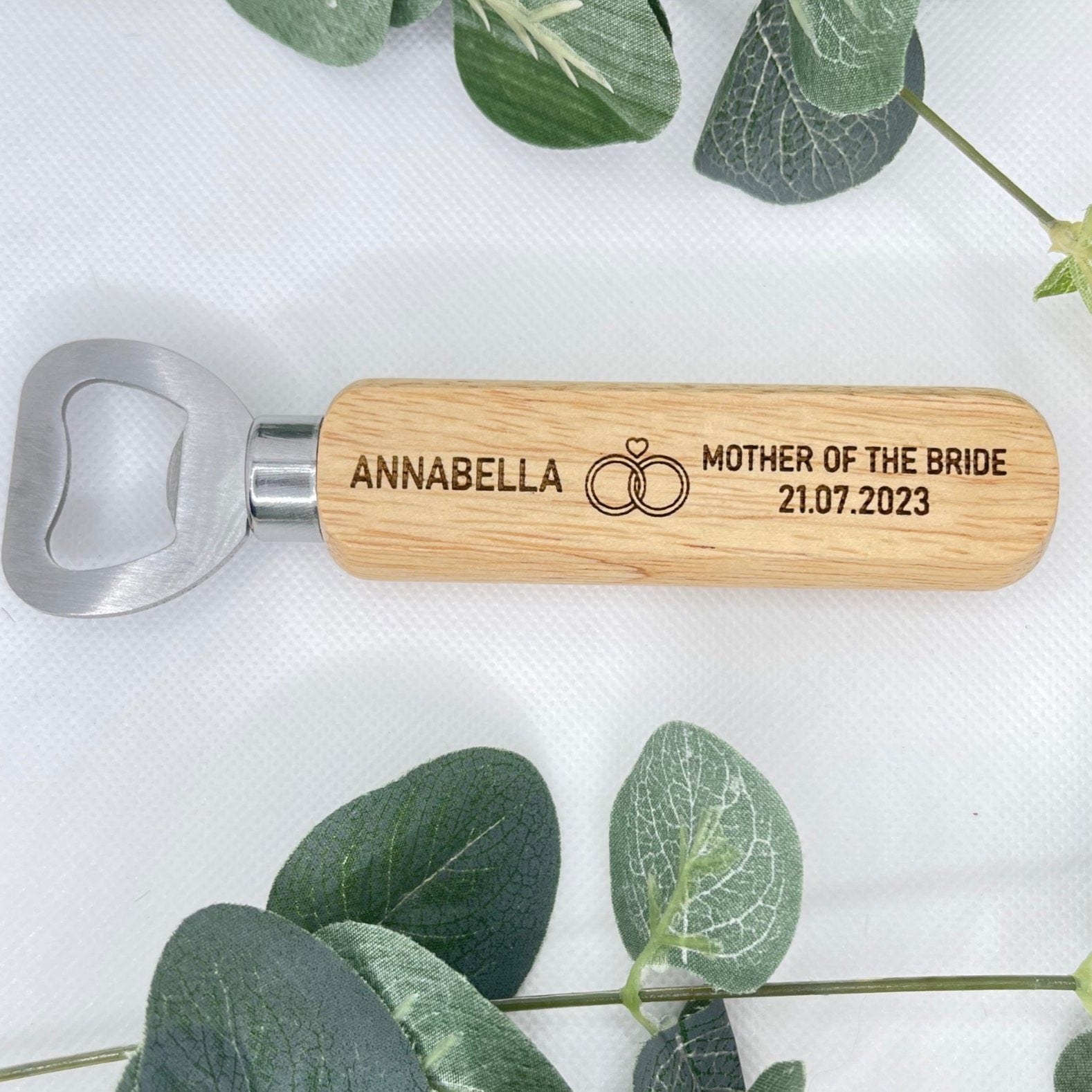 Close-up of the engraved names, wedding role, and date on the wooden handle of a bottle opener.
