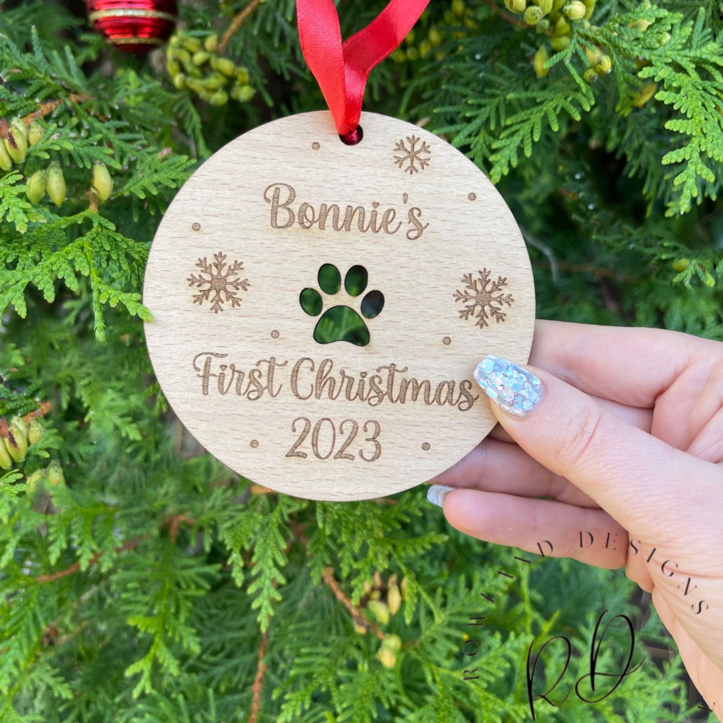 A custom engraved Christmas bauble with a paw print design and the dog's name.