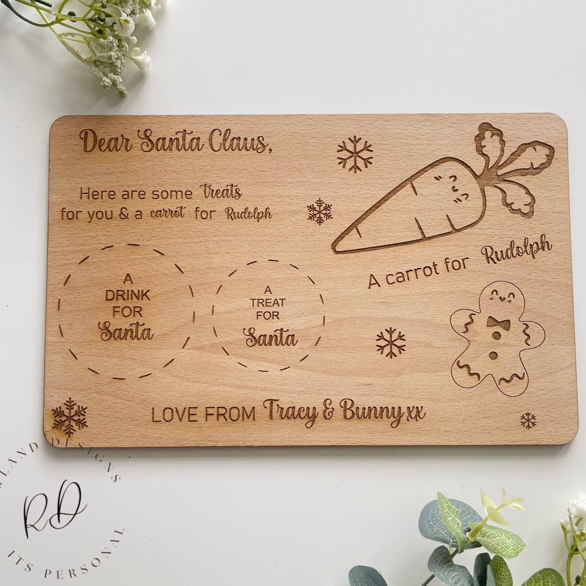 A close-up of a custom wooden Santa plate showing the engraved gingerbread and snowflake details.