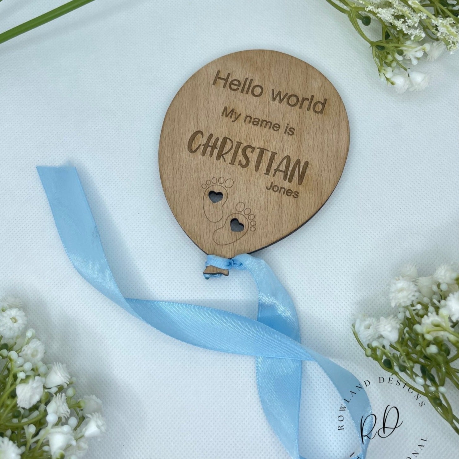 Close-up of an engraved plaque with a balloon and cloud design and a new baby's birth information.