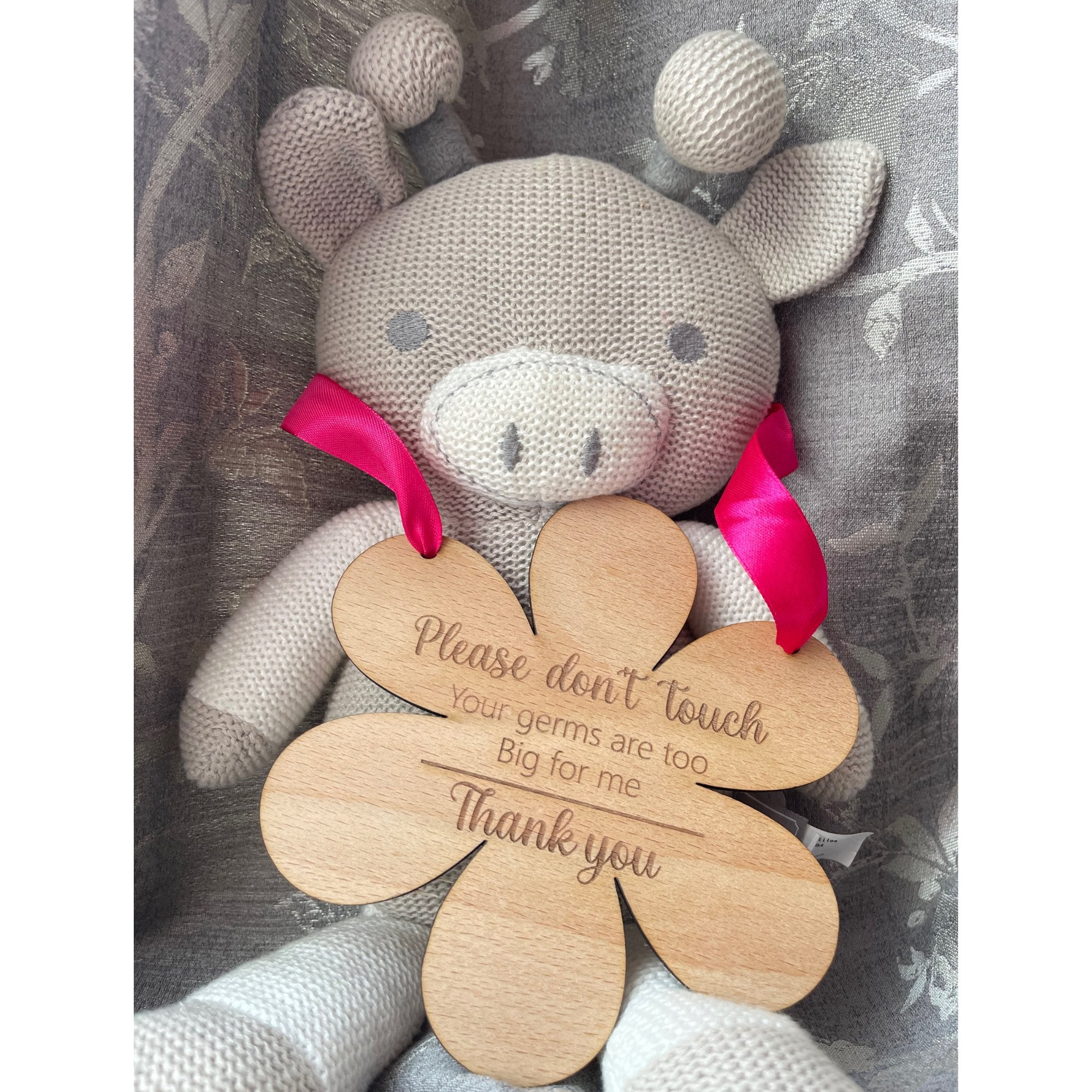 Mark the beauty of motherhood with our flower-shaped beech wood hanging sign, designed for both celebration and safety. Measuring 145mm by 148mm and crafted from robust 4mm wood, this enchanting piece doubles as a protective shield. Engraved with 'Please do not touch, your germs are too big for me, thank you,' and adorned with your choice of blue or pink ribbon.