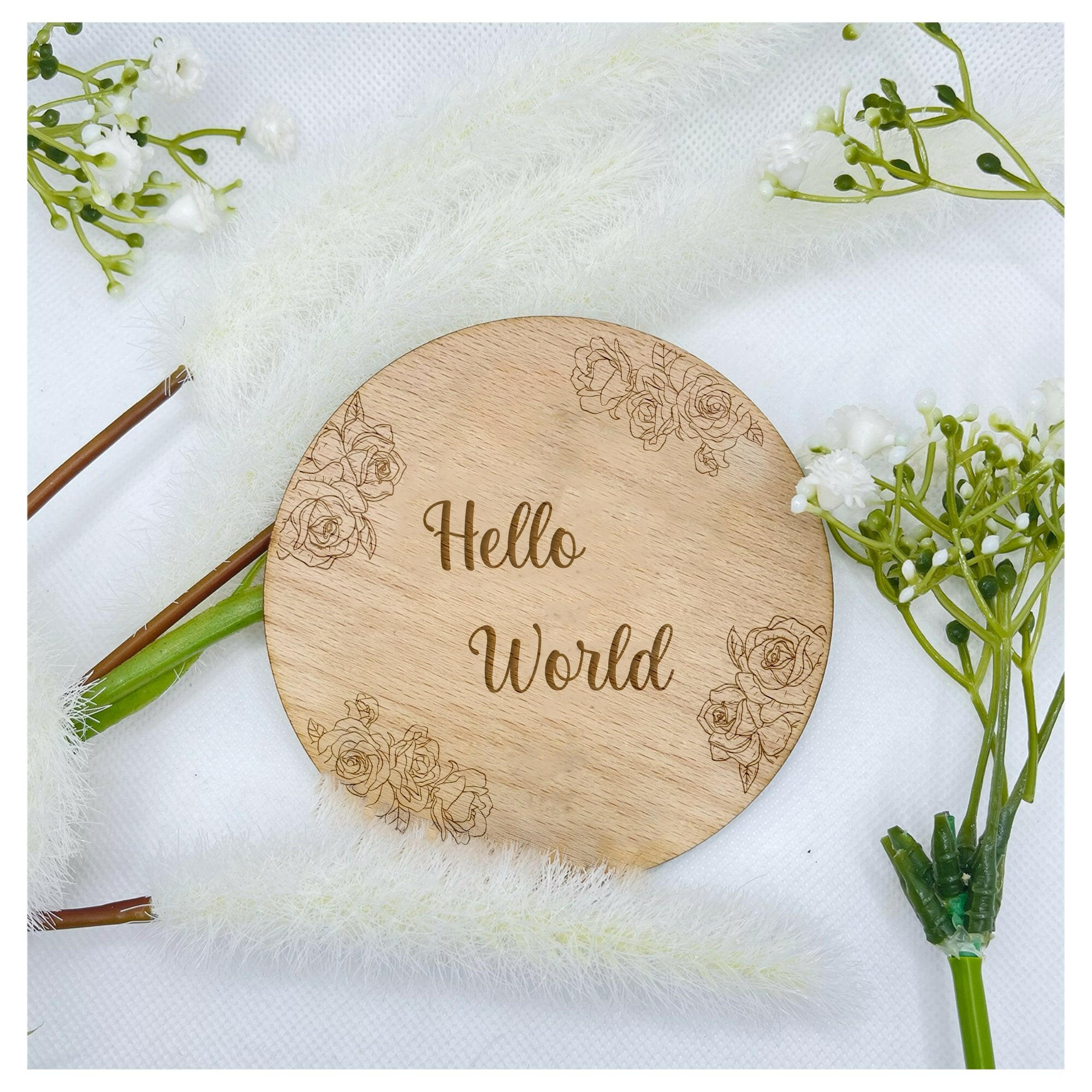 A wooden "Hello World" plaque with a delicate rose design, perfect for a baby announcement.