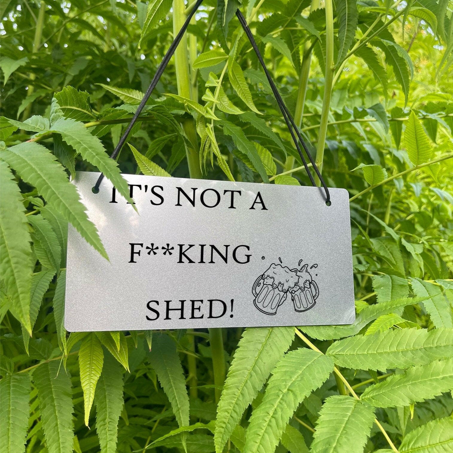 'IT'S NOT A F**KING SHED' and a beer glasses design, available in gold or silver.