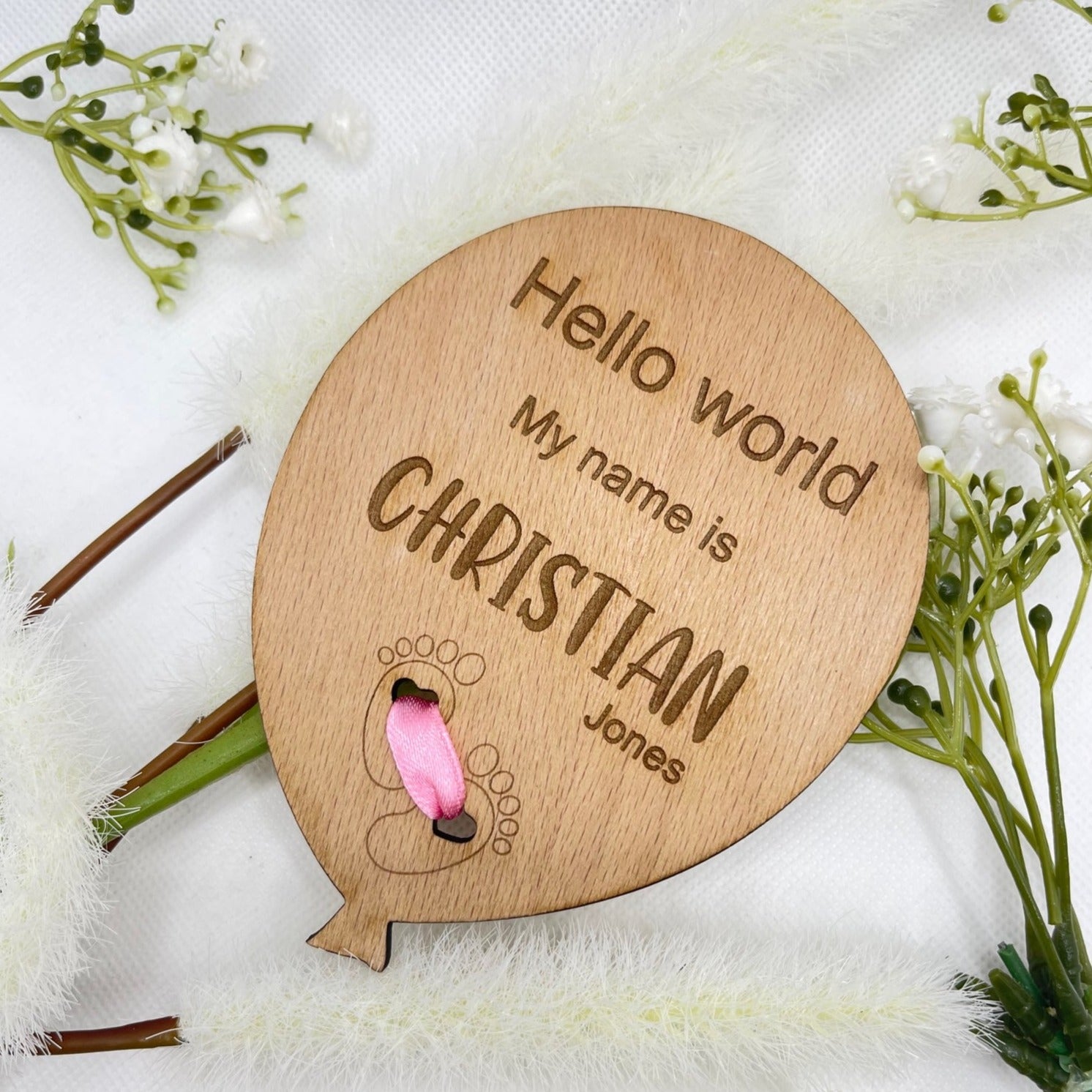 Personalised wooden baby announcement plaque with feet design, laid flat on its own.