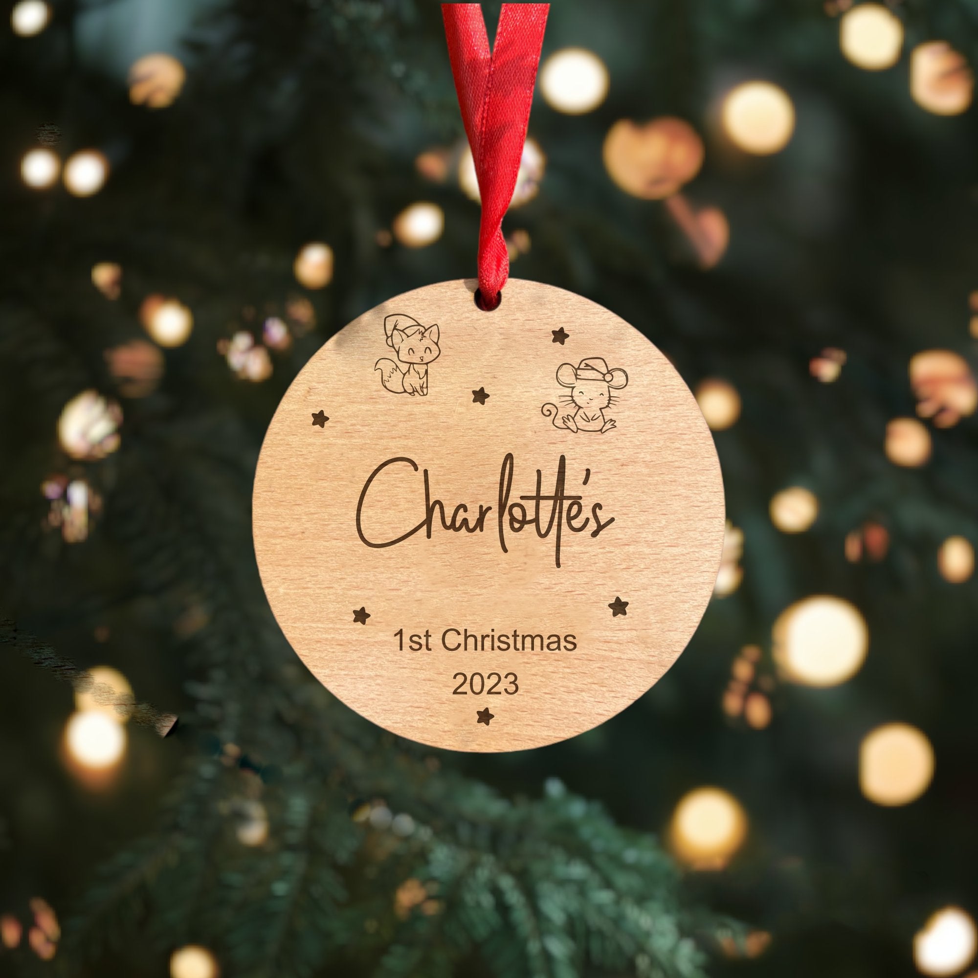 A personalised wooden bauble for a baby's first Christmas, with a custom name and a red ribbon.