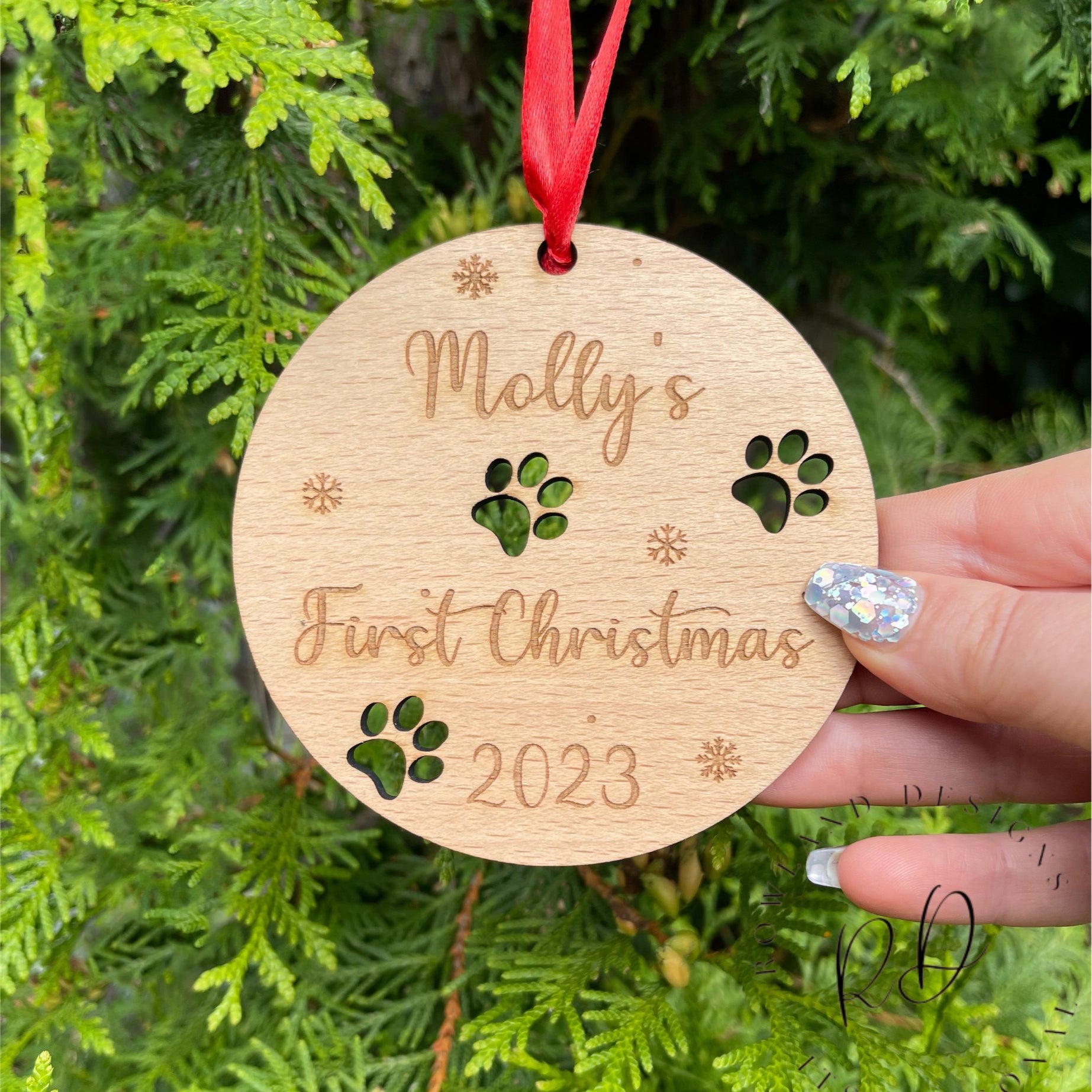 A personalised dog Christmas bauble for a "First Christmas" with an intricate paw print design.