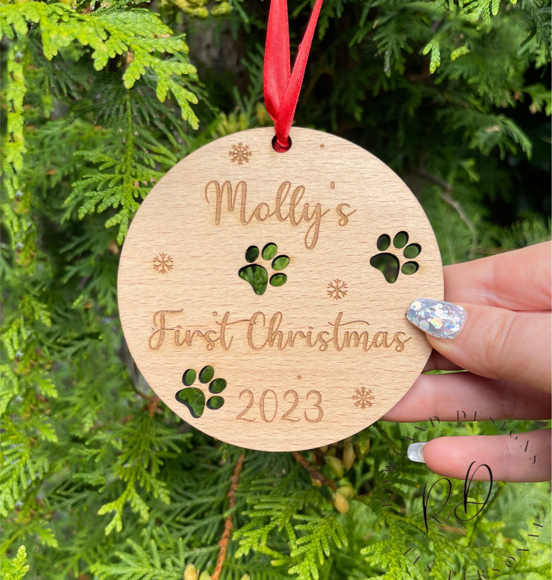 A personalised dog Christmas bauble for a "First Christmas" with an intricate paw print design.