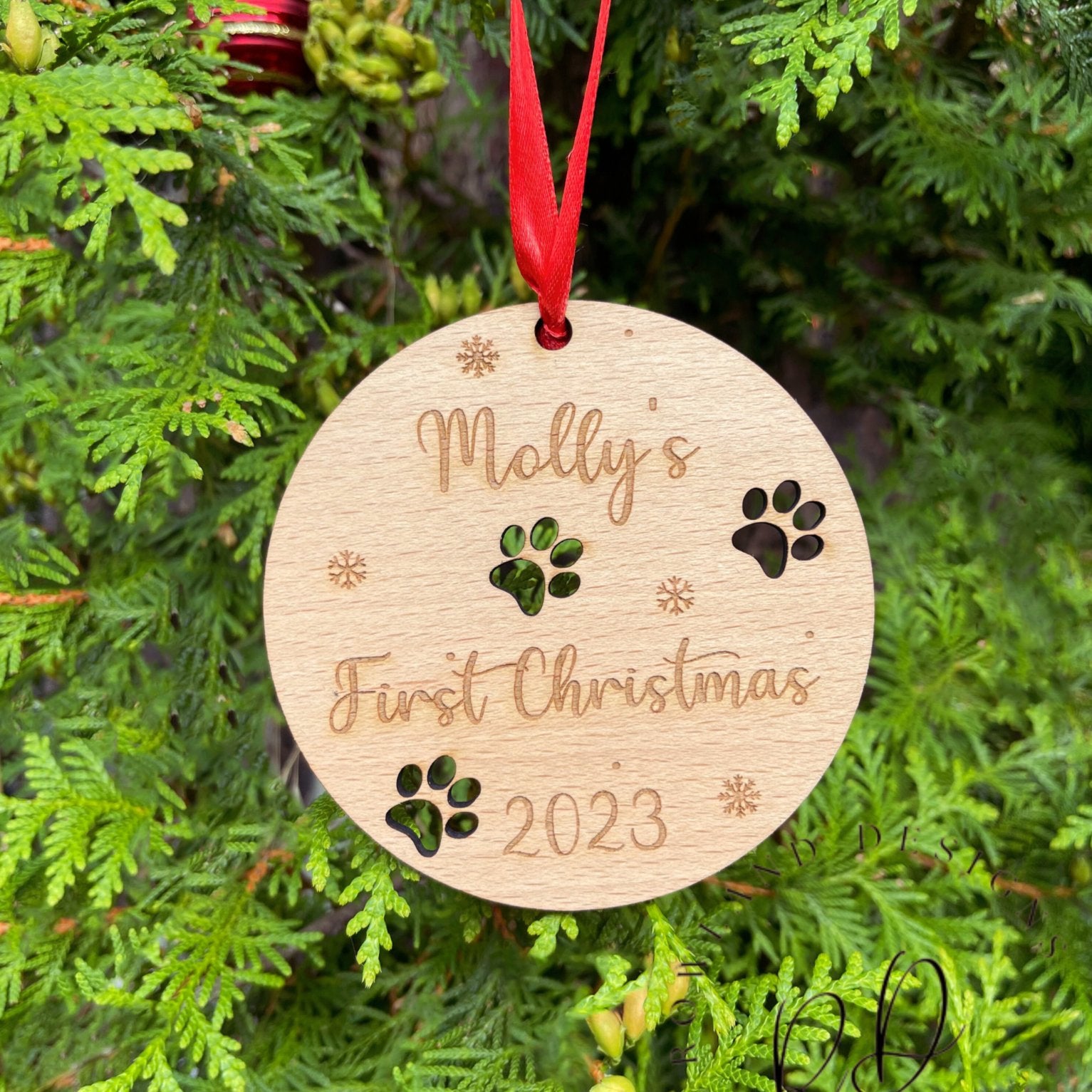 A round wooden Christmas decoration featuring a paw print pattern.