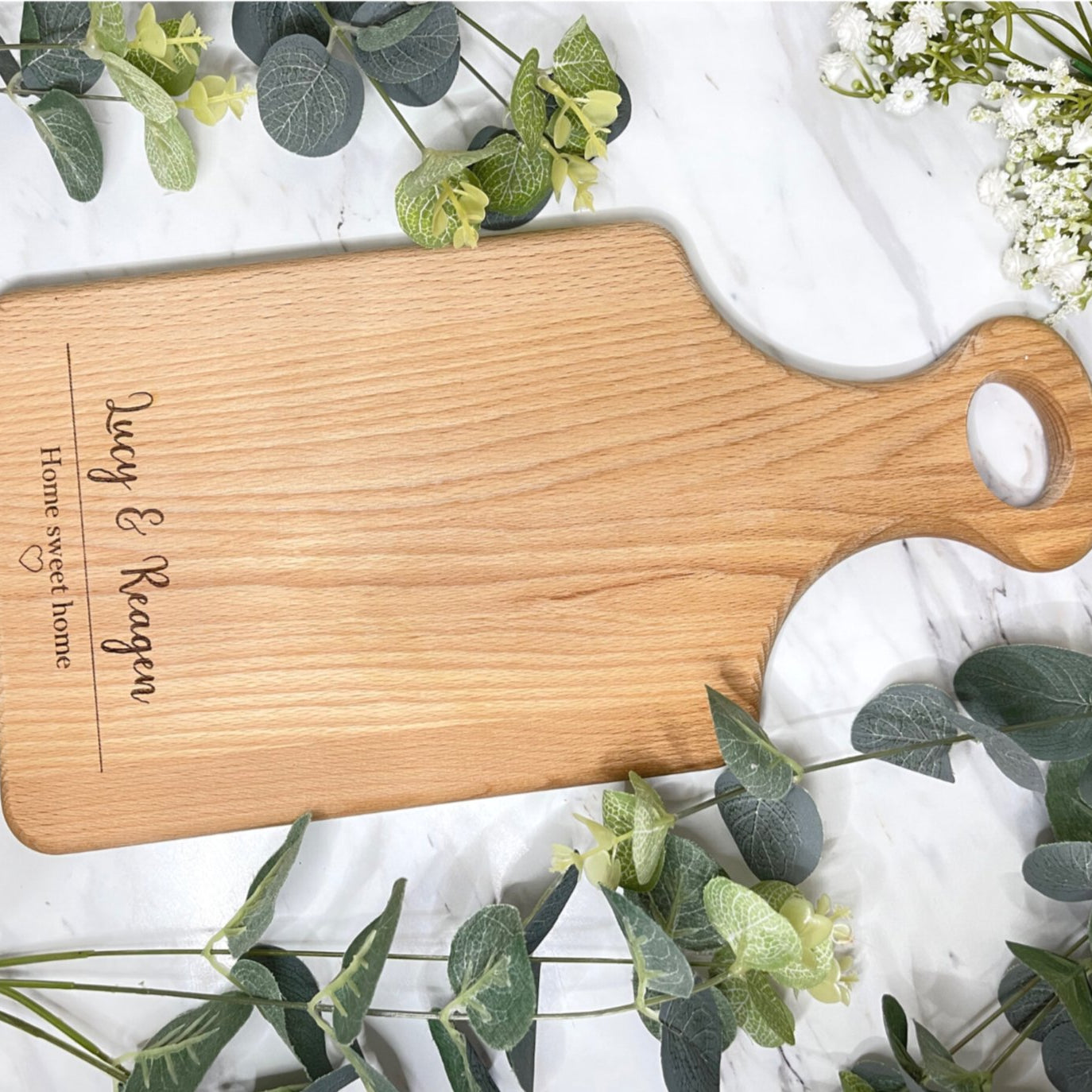 Personalised wooden "Home Sweet Home" serving board sitting on a kitchen countertop.
