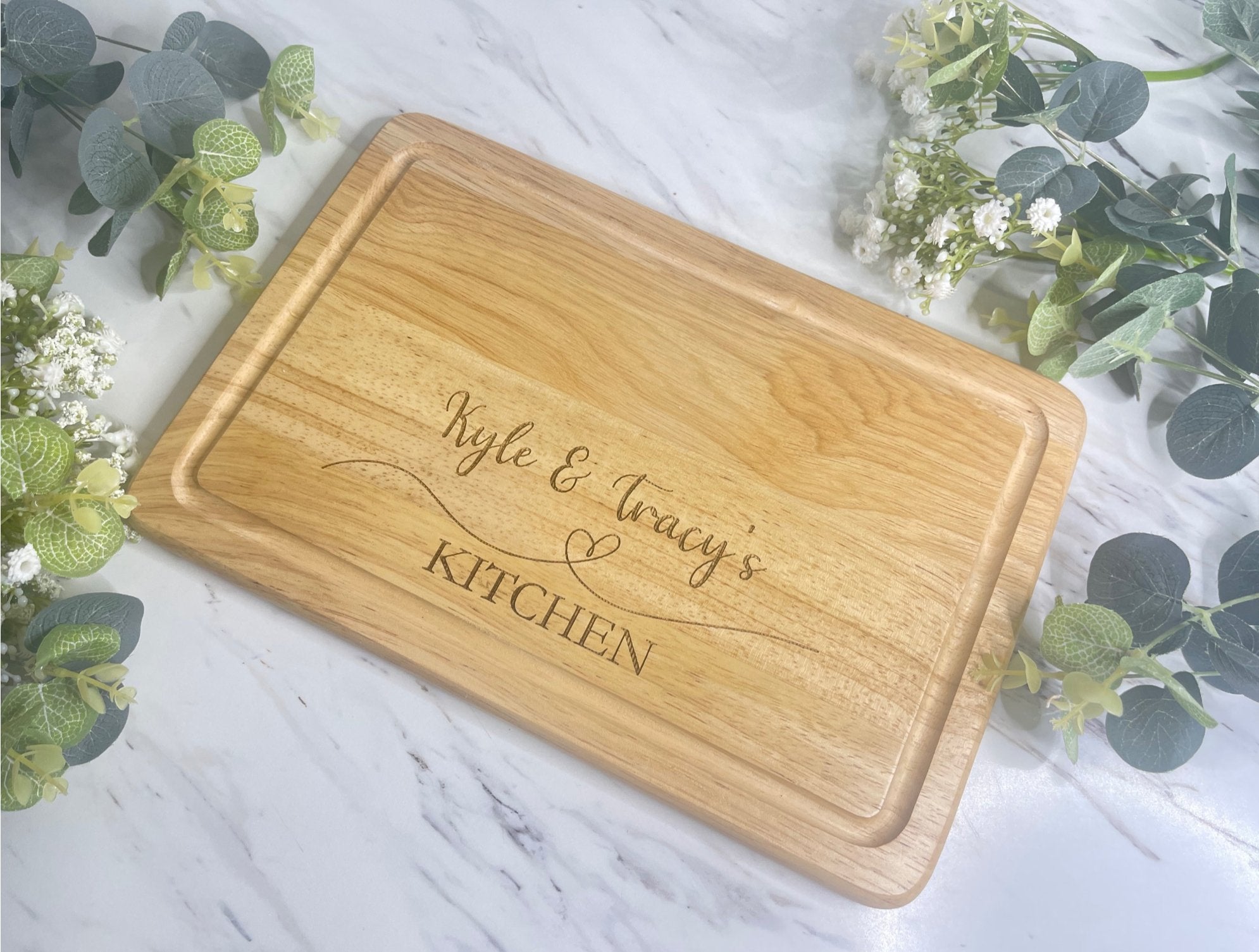 Personalised wooden chopping board with a heart design, with a name engraved on the left.