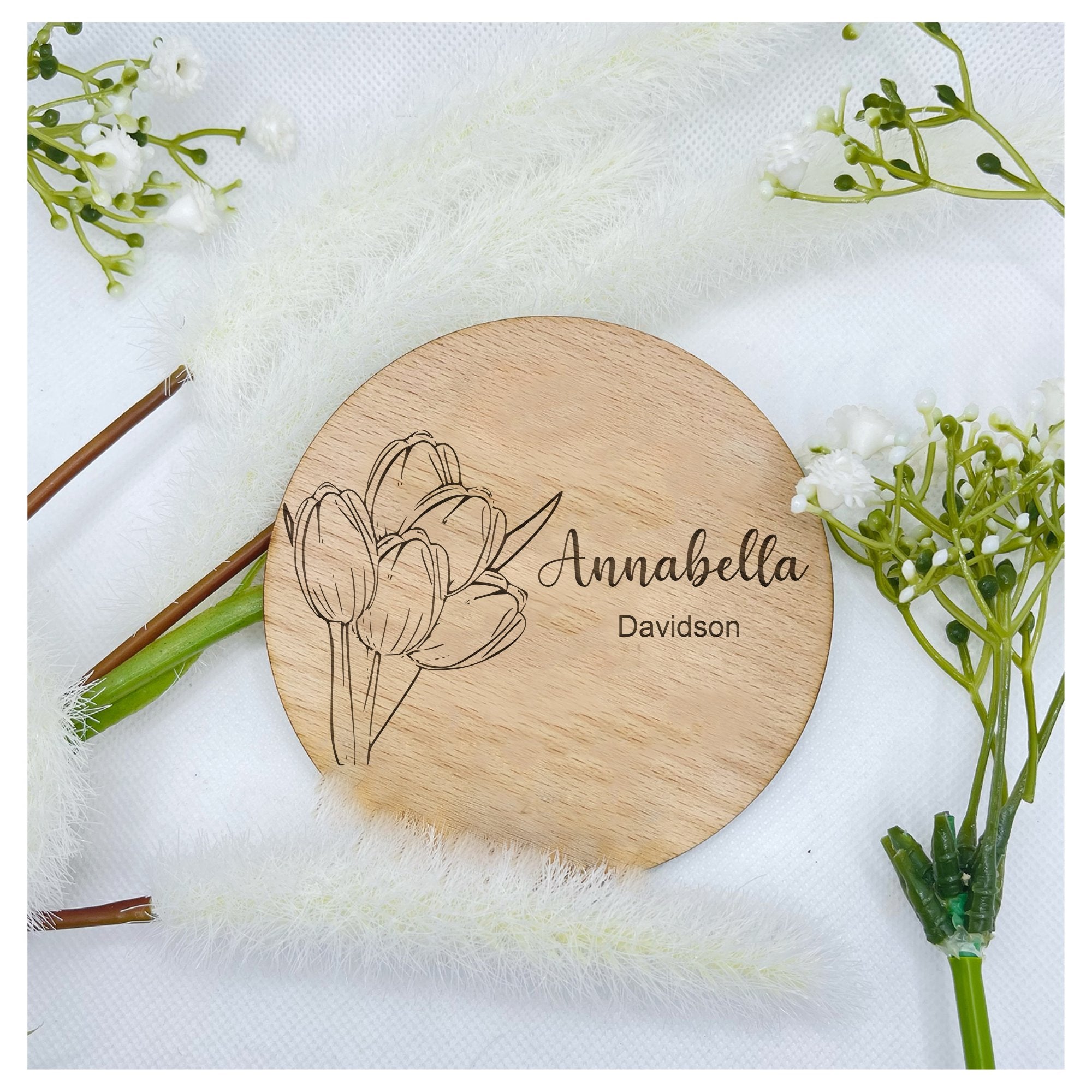 Detail shot of the round 10cm personalized wooden plaque showcasing the delicate laser-engraved tulip design.