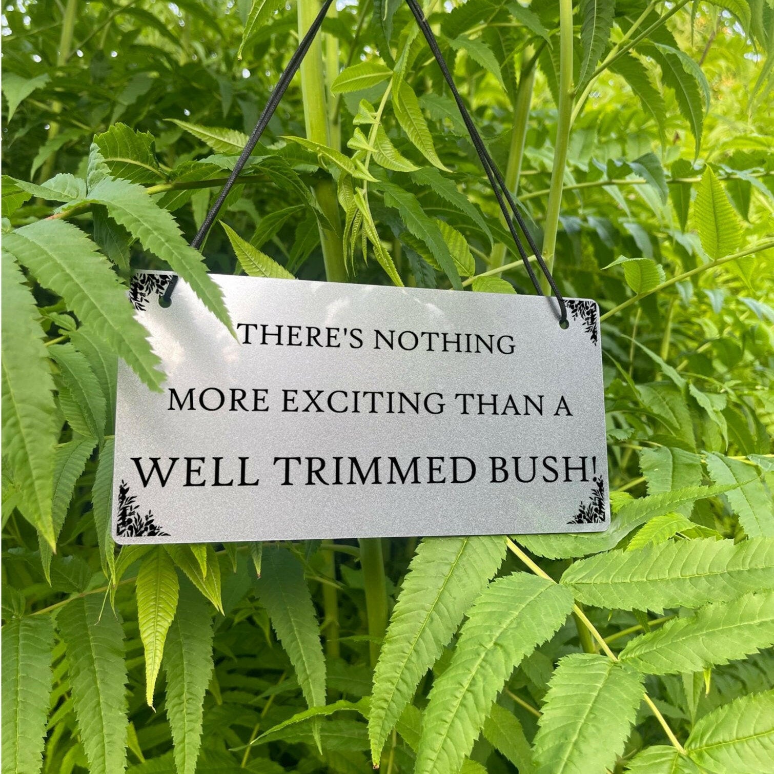 The humorous "Well Trimmed Bush" sign displayed hanging.
