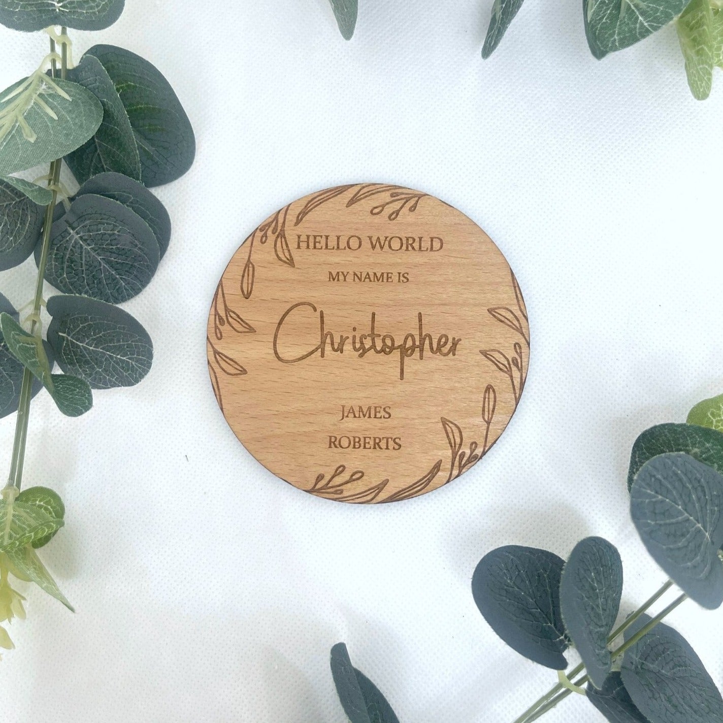 A wooden baby announcement sign with a bohemian leaf design, perfect for hospital photos.