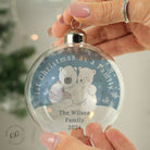 Bauble hanging on a decorated Christmas tree with lights and ornaments around it.