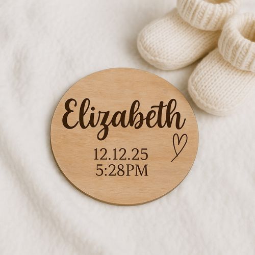 Round wooden disc with engraved name and date on a soft fabric background