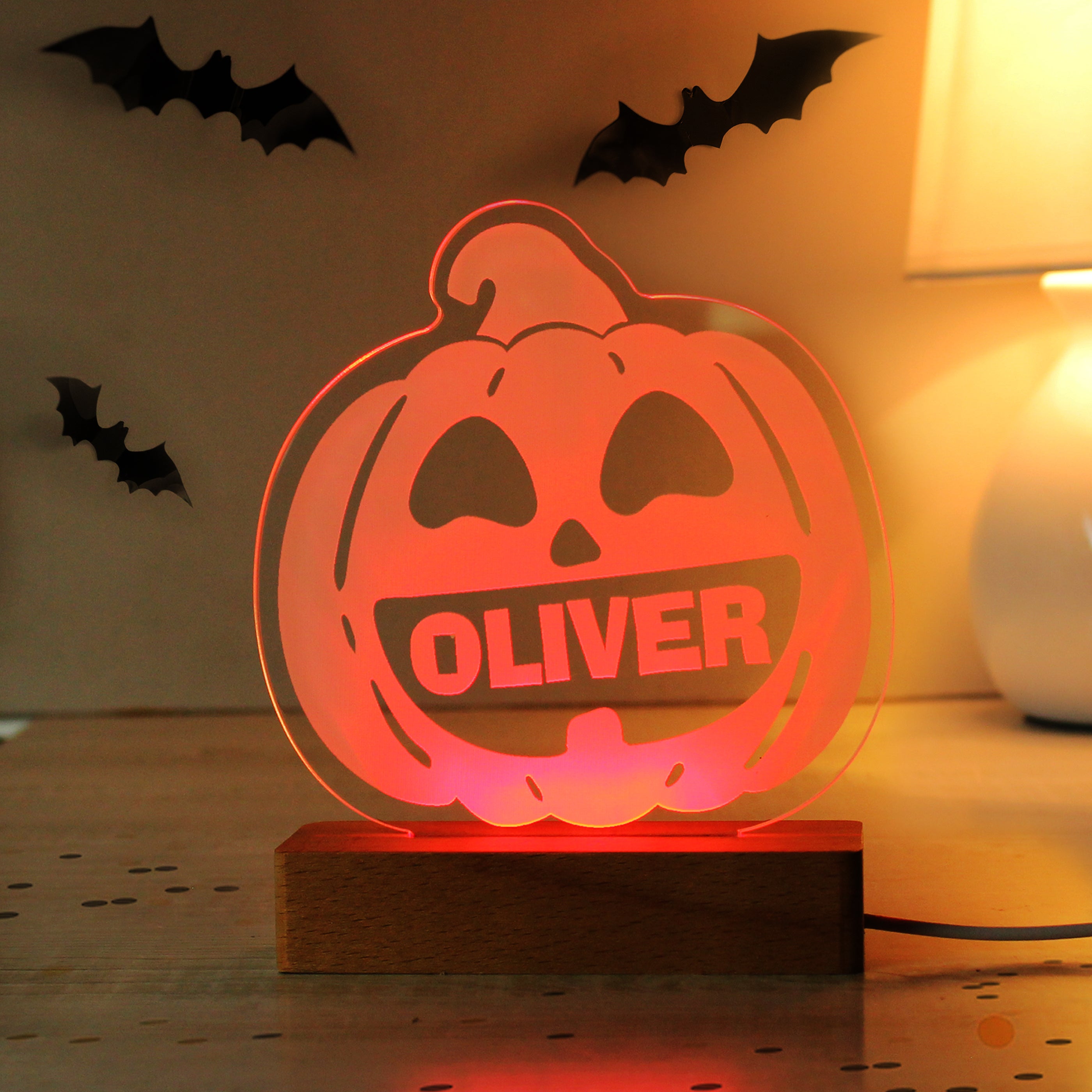 Halloween-themed pumpkin light with 'OLIVER' on a wooden base, surrounded by bats.