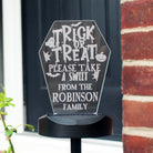 Halloween-themed sign with text 'Trick or Treat, please take a sweet from the Robinson family' on a black background.