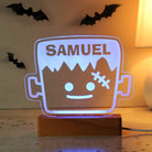 LED sign with 'SAMUEL' and a cartoonish design of a character in a glass container, with bats in the background.