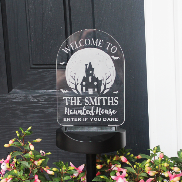 Decorative Halloween sign with a haunted house design on a black door.