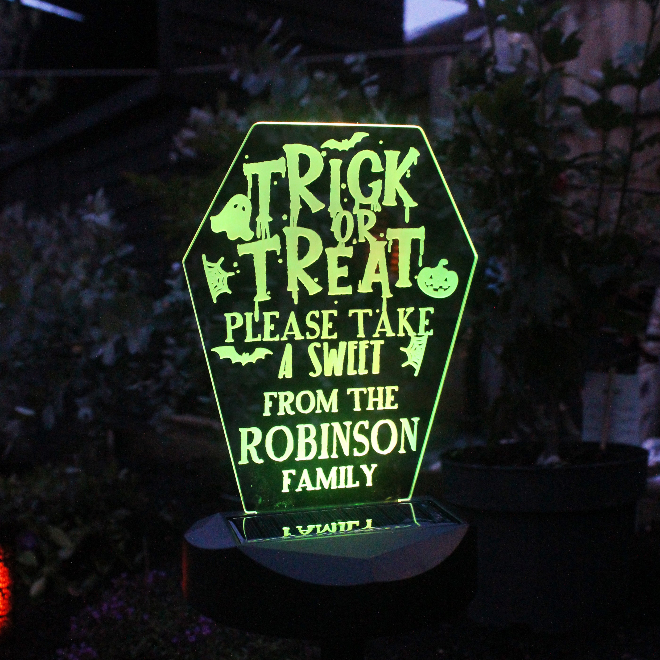 Glowing Halloween-themed sign with personalised text in a dark outdoor setting.