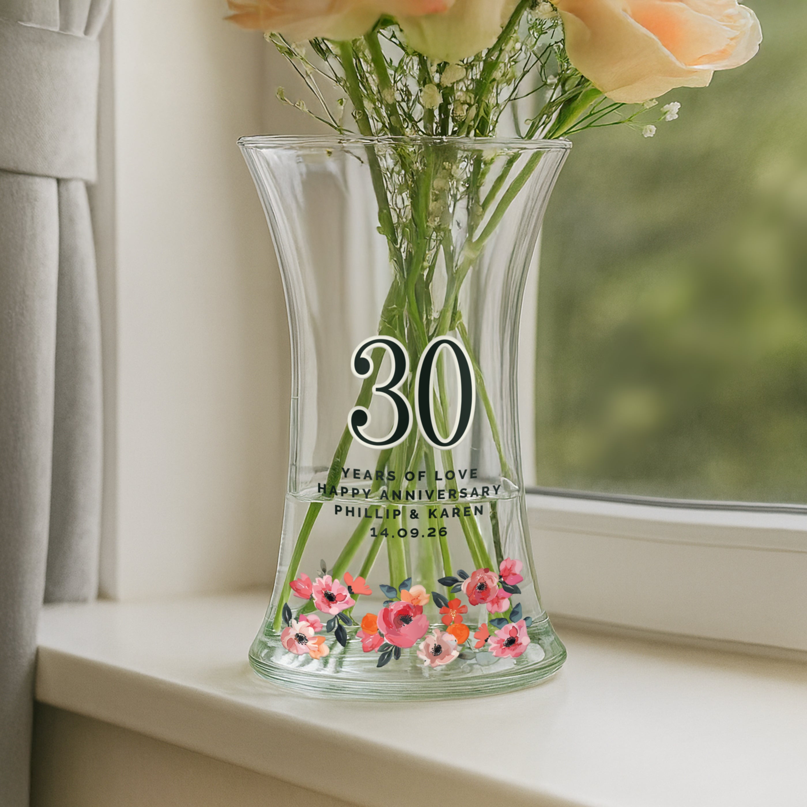 Clear glass vase with floral design and engraved text on a windowsill.