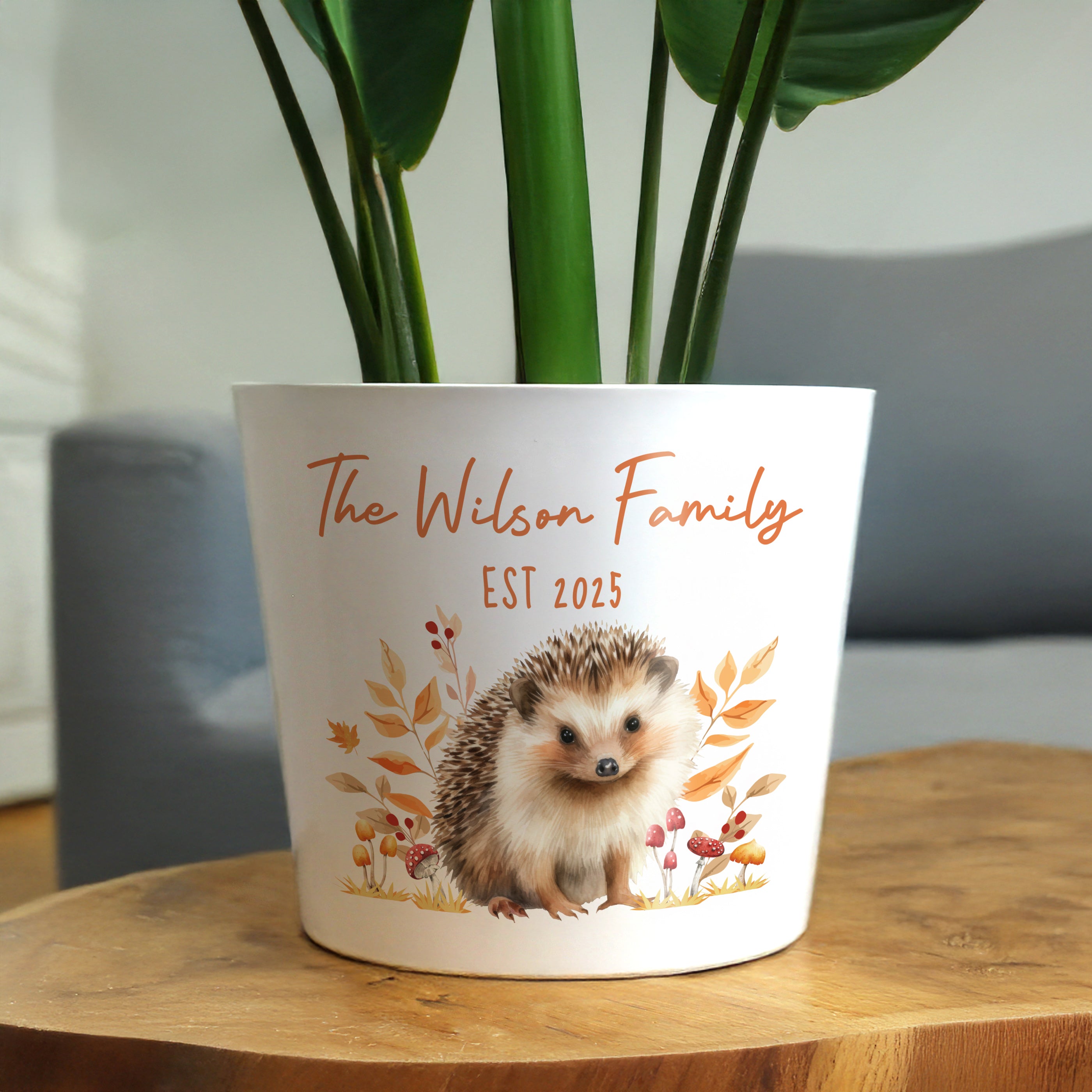 White pot with hedgehog design and 'The Wilson Family EST 2025' text on a wooden table.