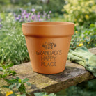 Terracotta pot with 'Grandad's Happy Place' text in a garden setting