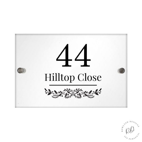 Modern acrylic house sign with leafy pattern displayed on wall