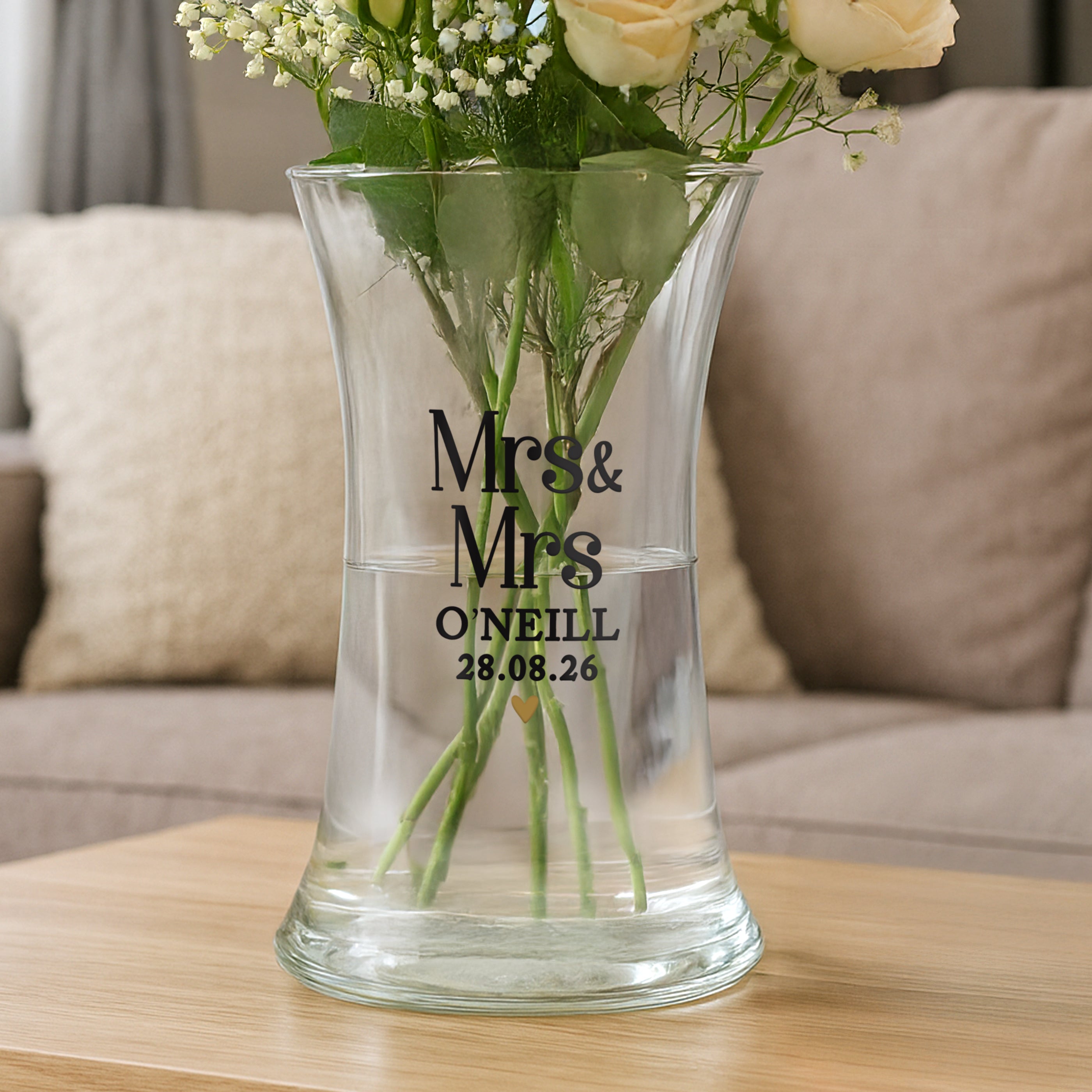 Clear glass vase with flowers and personalized text on a wooden table.