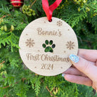 A personalised dog Christmas bauble for a "First Christmas" with a paw print cut out.