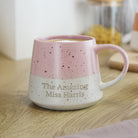 Pink speckled mug with 'The Amazing Miss Harris' text on a wooden surface.