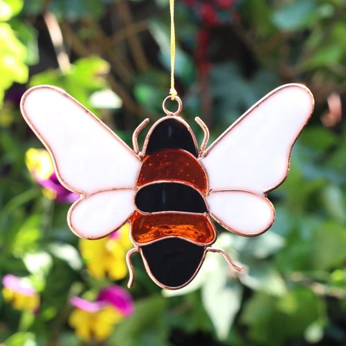 Resin bee suncatcher displayed in a garden setting.