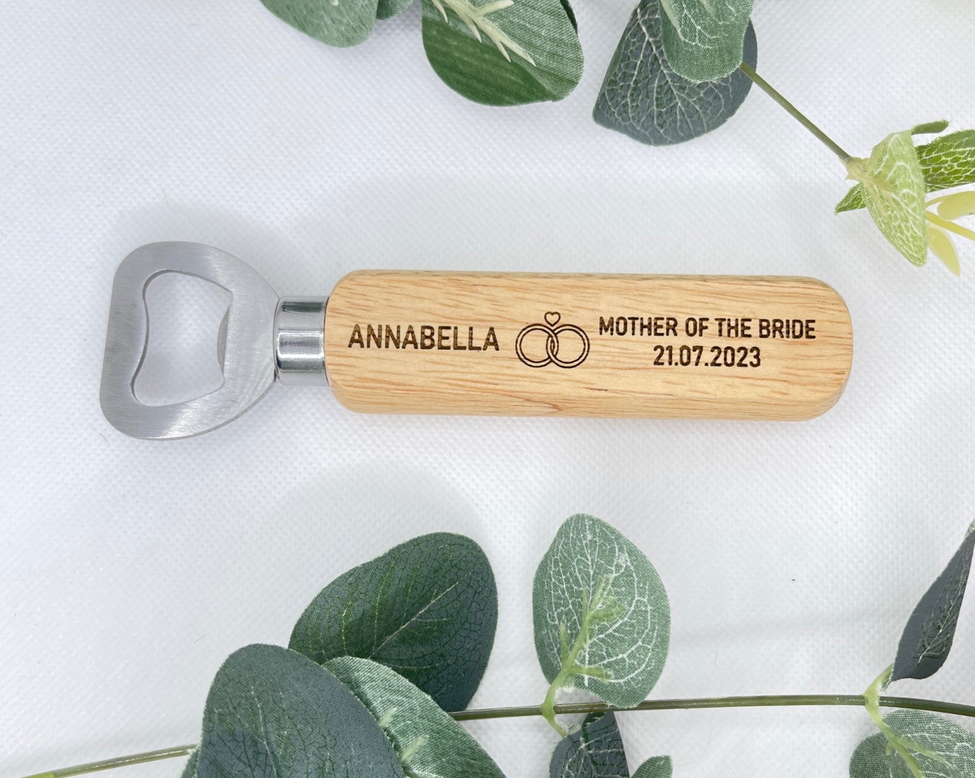 Close-up of engraved stainless steel bottle opener with wooden handle, featuring wedding guest details.