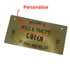Gold garden sign with black engraving and hanging twine, displayed outdoors.