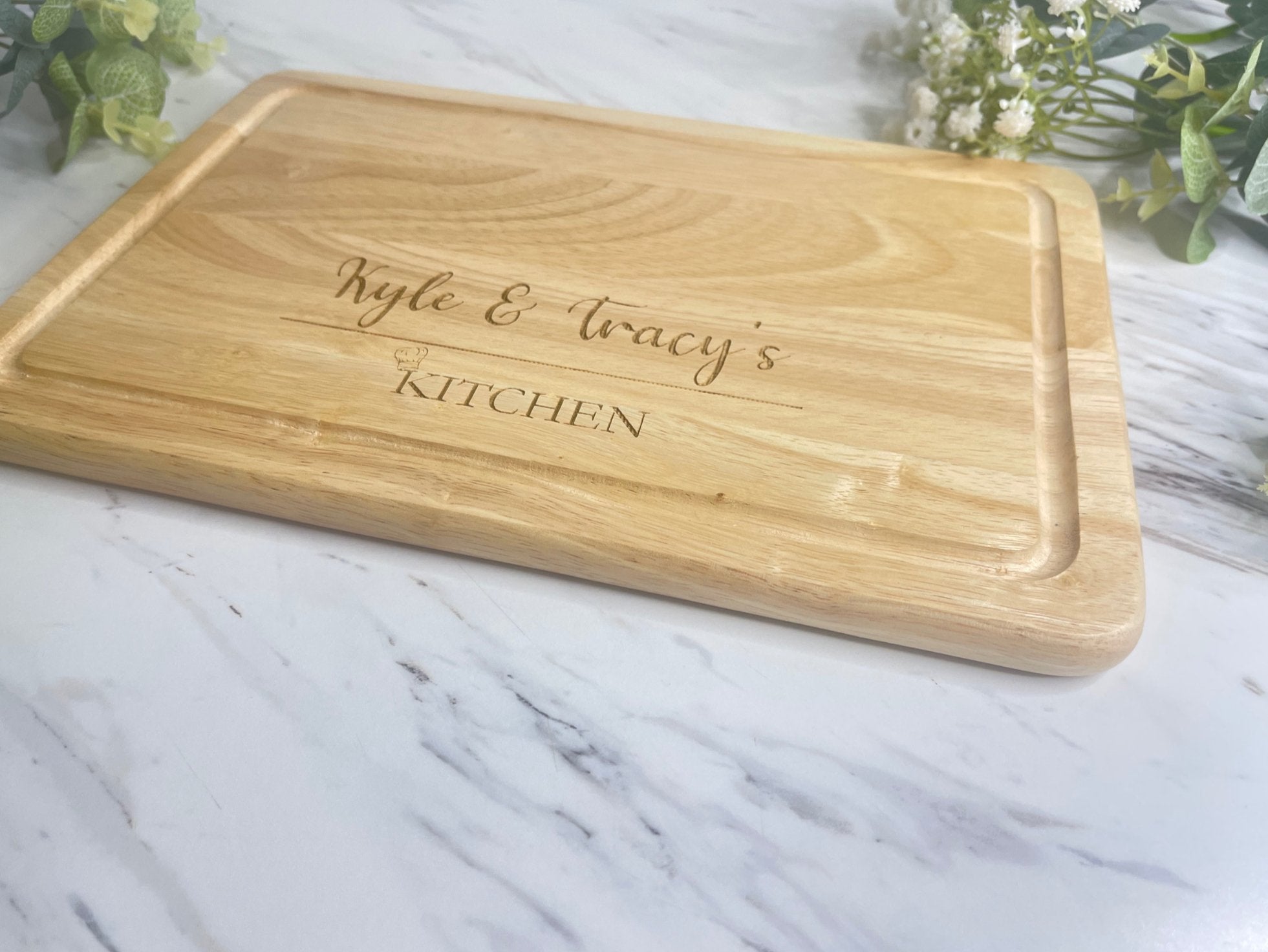 Close-up of the engraved name and chef hat on a personalised wooden chopping board.