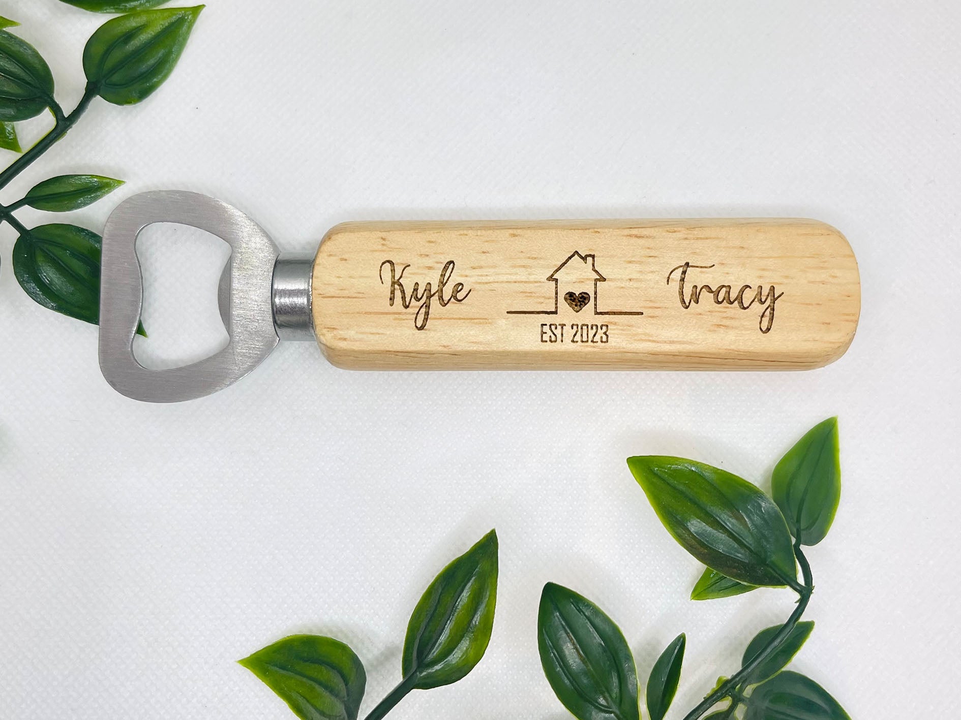 Close-up of the engraved names and date on a wooden bottle opener for an anniversary gift.
