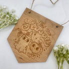 Image: A charming Halloween hanging sign, featuring an adorable ghost and pumpkin illustration. The sign bears the festive words 'Tis The Season,' making it perfect for indoor display to create an extra festive atmosphere during the spooky season.