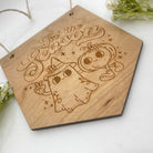 Product Image: Elevate your Halloween decor with our delightful hanging sign. This piece showcases a cute ghost and pumpkin illustration, accompanied by the words 'Tis The Season' for a festive touch. Hang it indoors to infuse your space with the spirit of the season.
