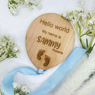 Personalised wooden baby announcement plaque with a feet design and a blue ribbon.