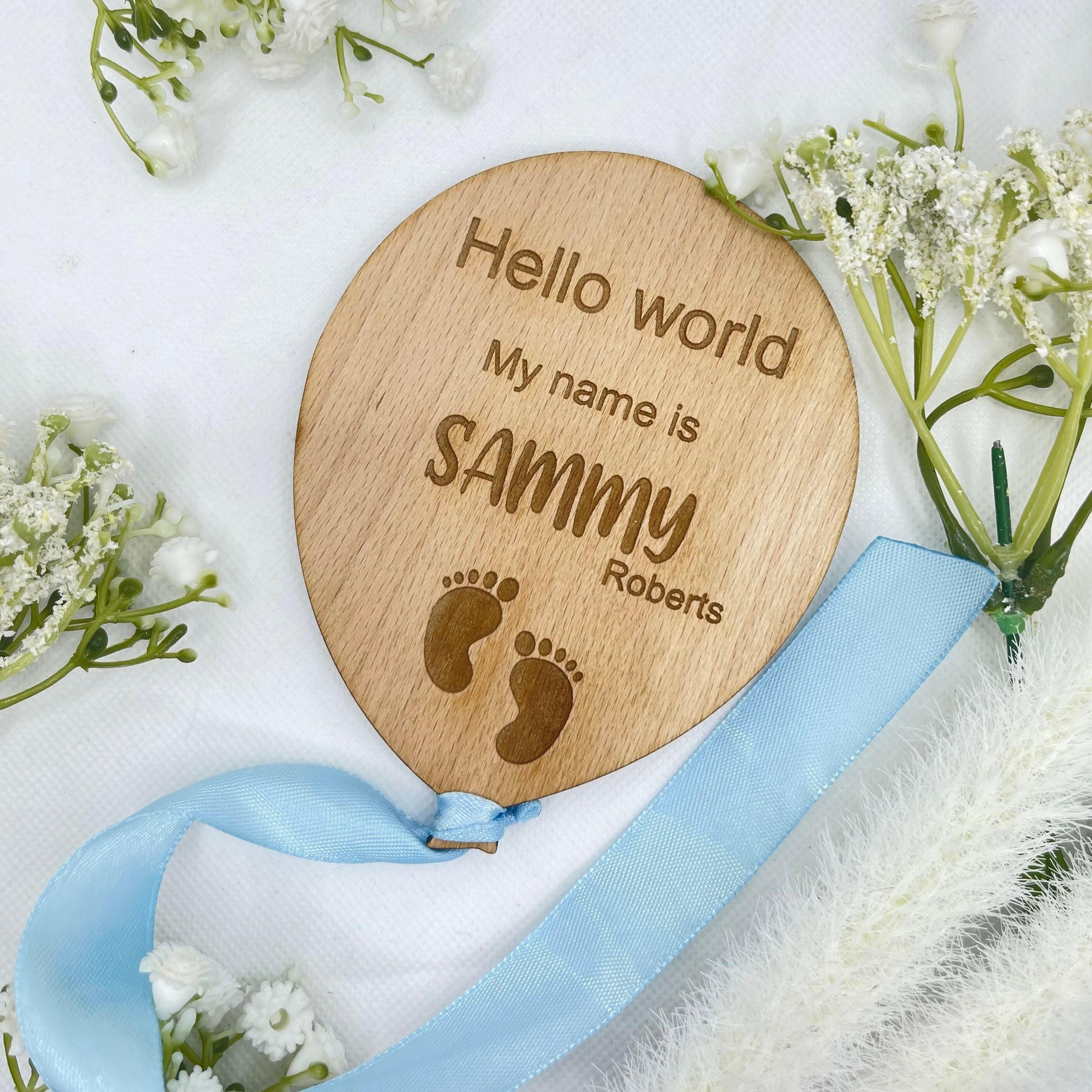 Personalised wooden baby announcement plaque with a feet design and a blue ribbon.